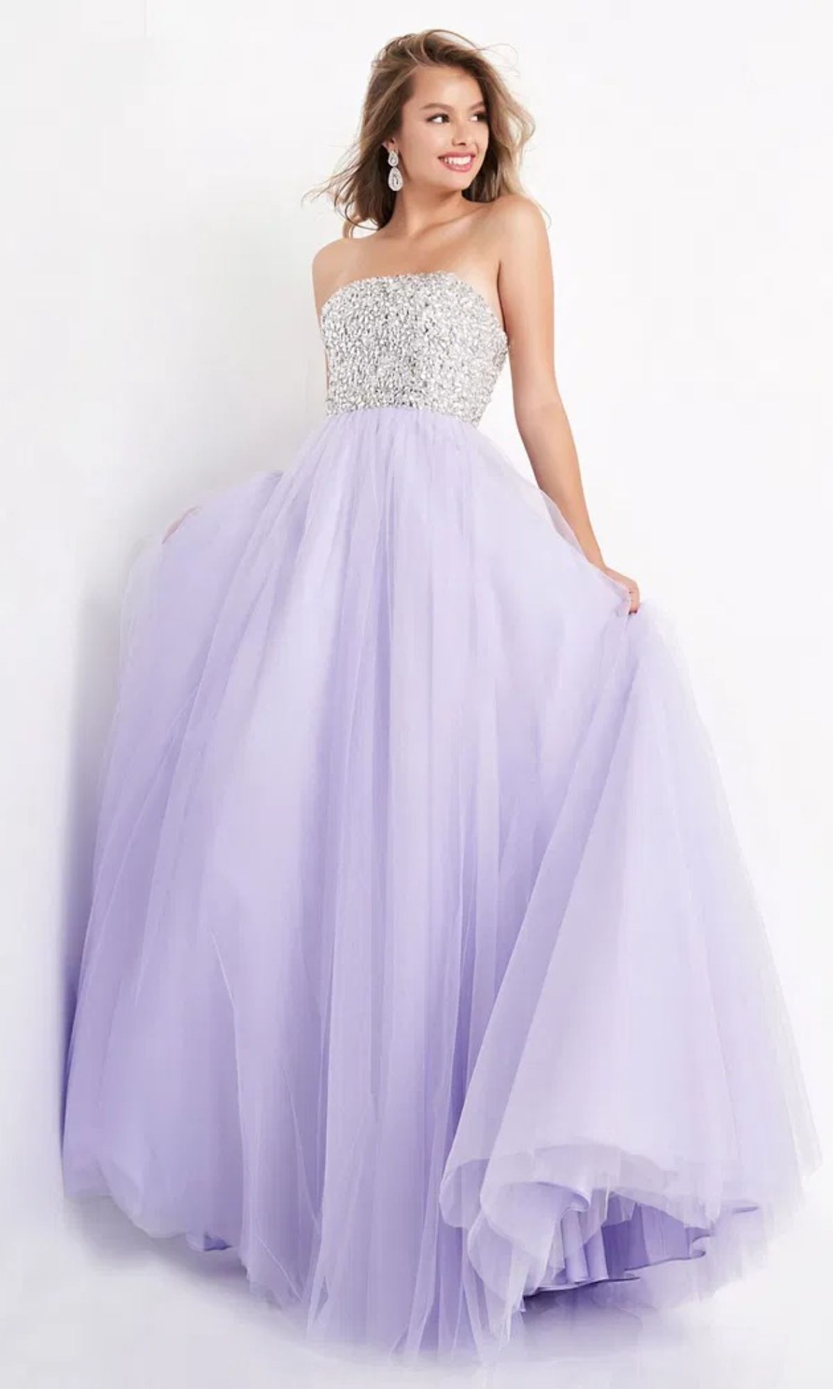 A woman wearing the Jovani 52131 Long Strapless Ball Gown Prom Dress, featuring a beaded silver bodice and full lavender tulle skirt, stands against a plain background.